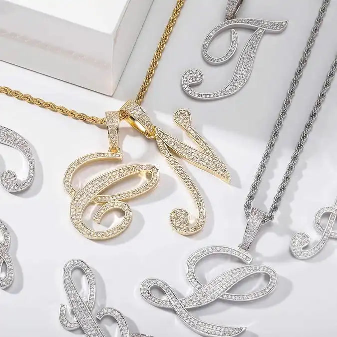Decorative initial letter pendants with diamonds in gold and silver finishes on chains.