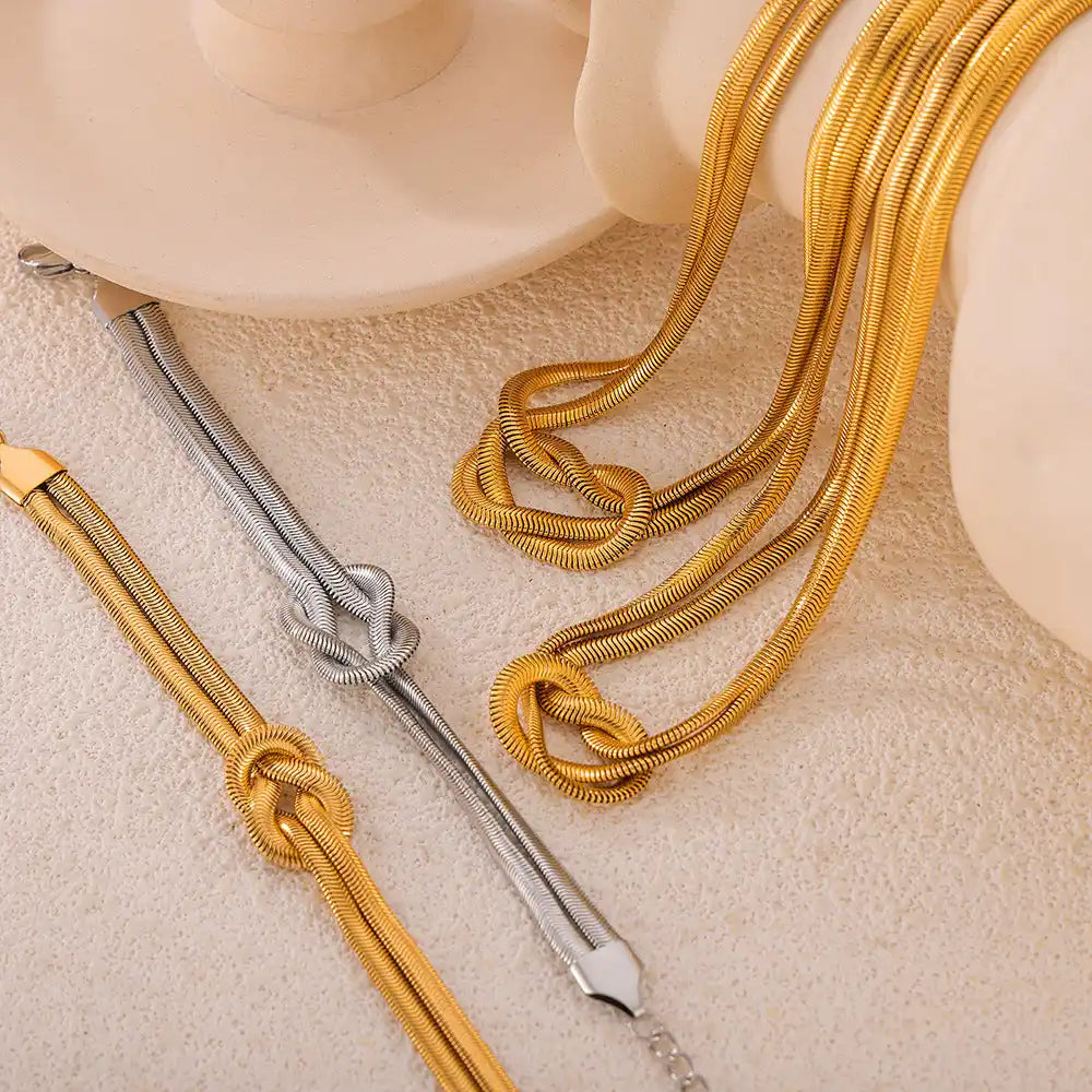 Gold and silver snake chain bracelets with knot designs.
