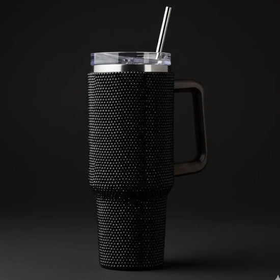 Black rhinestone-encrusted insulated tumbler with a clear lid and stainless steel straw.