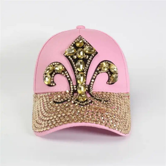 A pink baseball cap adorned with a gold rhinestone fleur-de-lis and a sparkly brim.