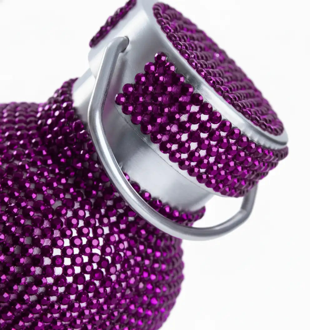 A sparkling purple water bottle adorned with a dense layer of rhinestones and featuring a sleek silver-toned metal cap and handle.