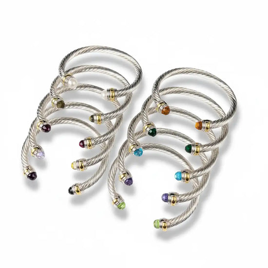 Silver cable bracelet cuffs adorned with colorful gemstones and gold-tone accents.