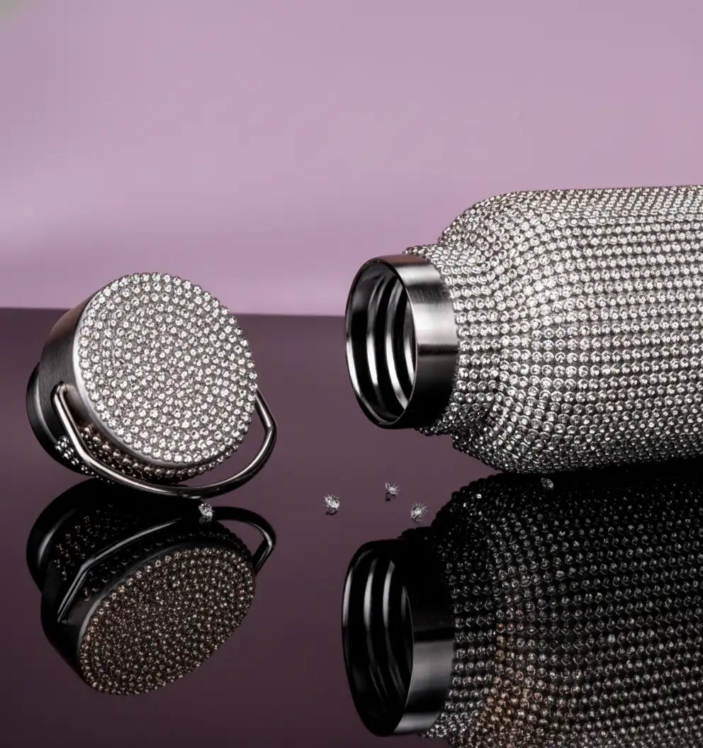 A sparkling silver water bottle adorned with a dense, glittering array of clear rhinestones covering its entire surface and matching lid.