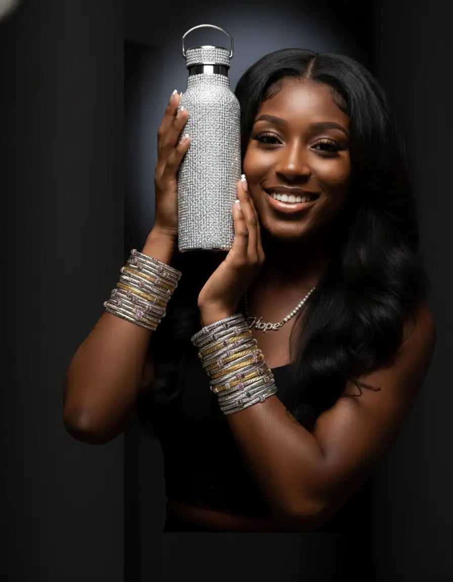 A sparkling silver water bottle adorned with a dense array of rhinestones and featuring a sleek, metallic handle.