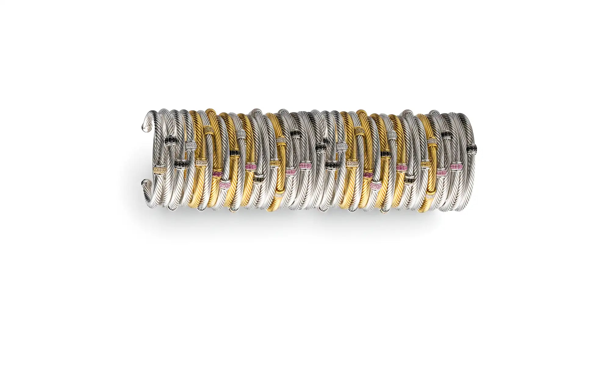 A stack of elegant, twisted metal bangles in silver and gold tones with small pink gemstone accents.