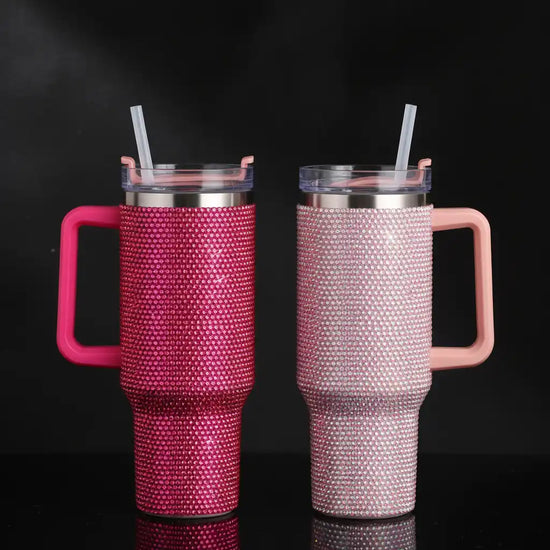 Two rhinestone-studded tumblers with handles and straws.