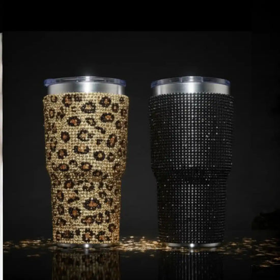 Two sparkling tumblers, one with a leopard print and one black, both adorned with rhinestones.